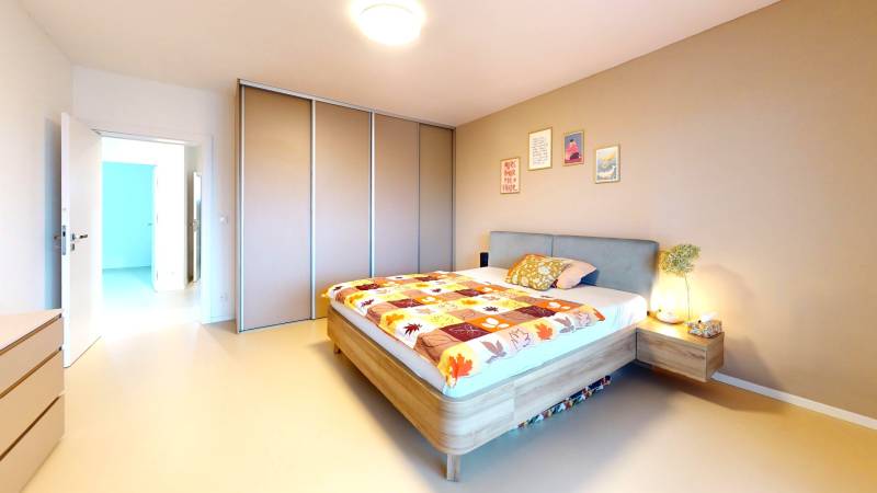 A bedroom in a family house with a colorful bedspread and a large built-in wardrobe.