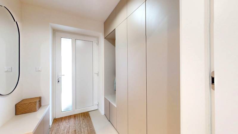 Entrance hallway of a family house with a coat closet, mirror, and carpet.