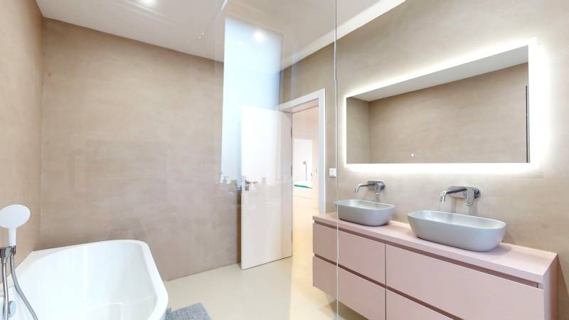 A bathroom with a bathtub, two sinks, and a mirror in a family house.