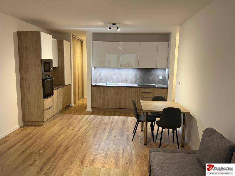 A kitchen in a 2-room apartment with a wooden decor floor and a dining table.