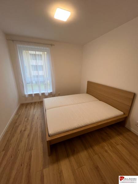 A bedroom with a bed, a floor with a wooden decor in a 2-room apartment.