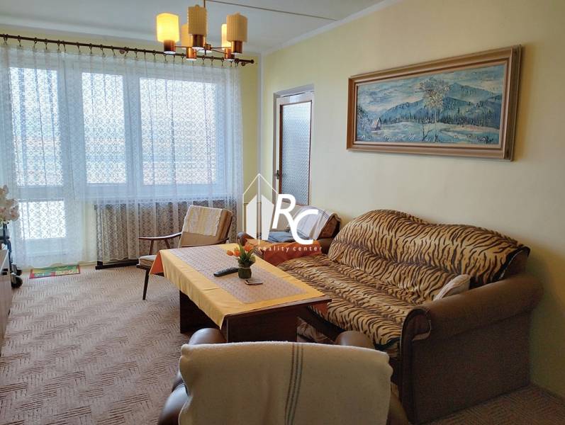 Living room with a sofa, armchair, and table in a 2-room apartment with a large window.