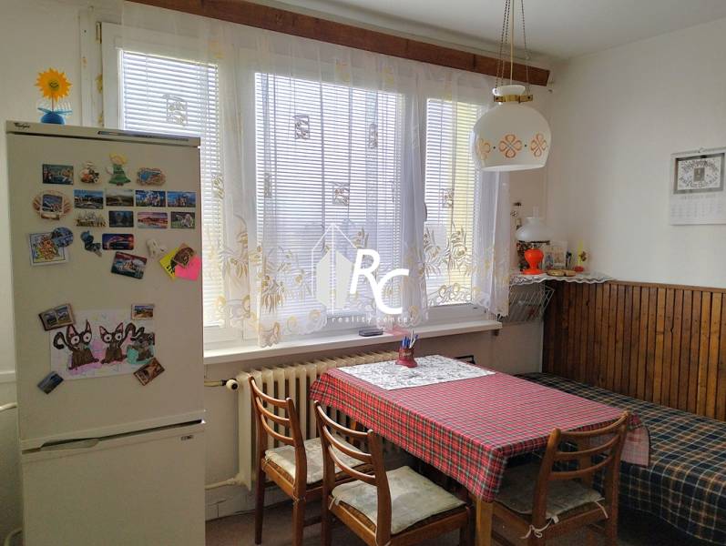 A kitchen in a 2-room apartment with a dining table, chairs, and a fridge with magnets.