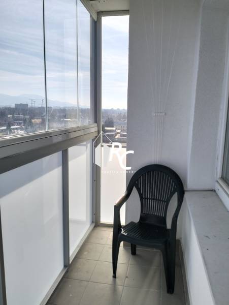 Glazed balcony with a view and a plastic chair, part of a 2-room apartment.