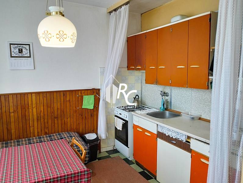A kitchen with older furniture in a 2-room apartment, orange cabinets, table, chandelier.