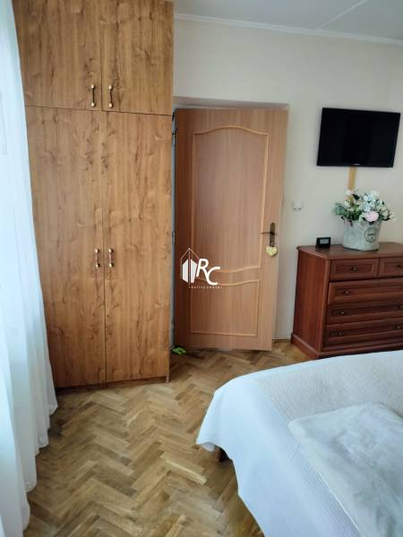 A bedroom in a two-room apartment with a wooden decor floor, a wardrobe, and a television.