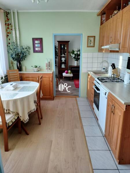A kitchen in a 2-room apartment with a wooden decor floor and a table in the corner of the room.