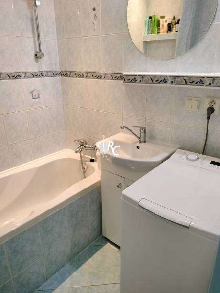 Bathroom of a two-room apartment with a bathtub, sink, and washing machine.