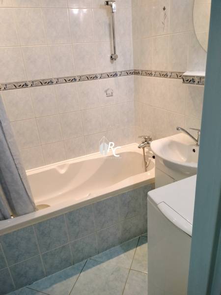 Bathroom in a 2-room apartment with a bathtub and light tiles.