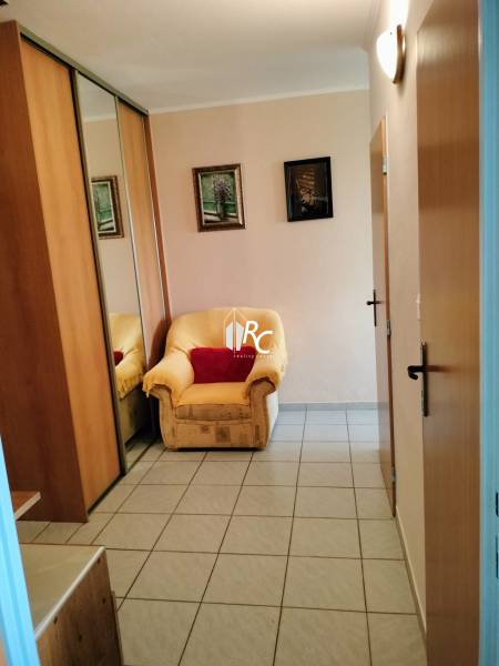 An armchair by the entrance door with a tiled floor in a 2-room apartment, mirrored wardrobe.