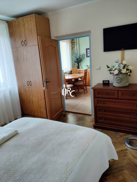 Bedroom with a built-in wardrobe in a 2-room apartment, floor with wooden decor, doors lead to the kitchen.