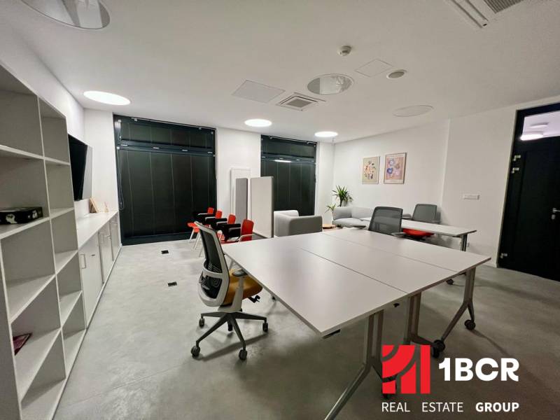 An office with white furniture, two desks, and shelves in a two-room apartment.