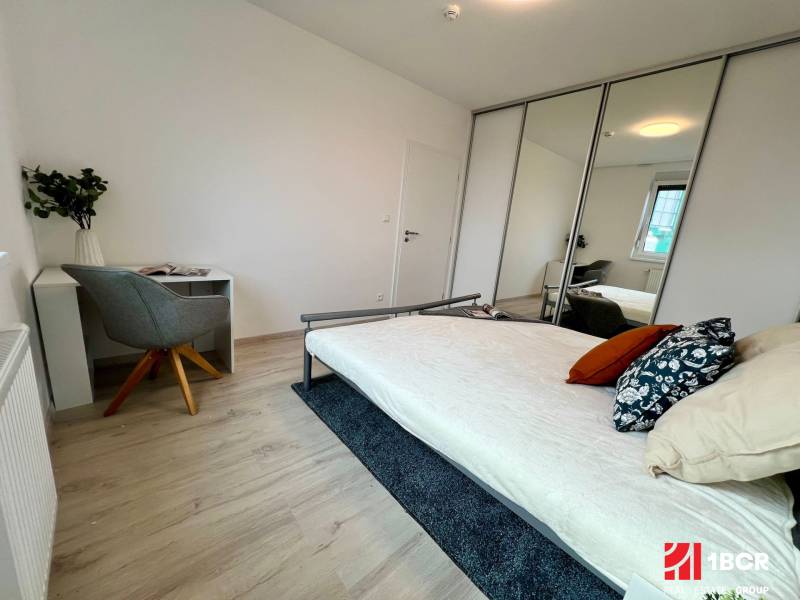 Bedroom in a 2-room apartment with a bed, a desk, and a mirrored wardrobe.