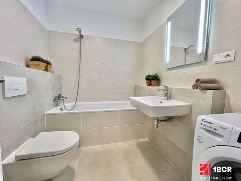 Bathroom in a 2-room apartment with a shower, bathtub, washing machine, and sink.