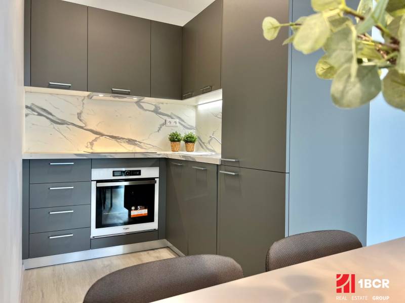 A kitchen in a 2-room apartment with stone cladding and gray cabinets.