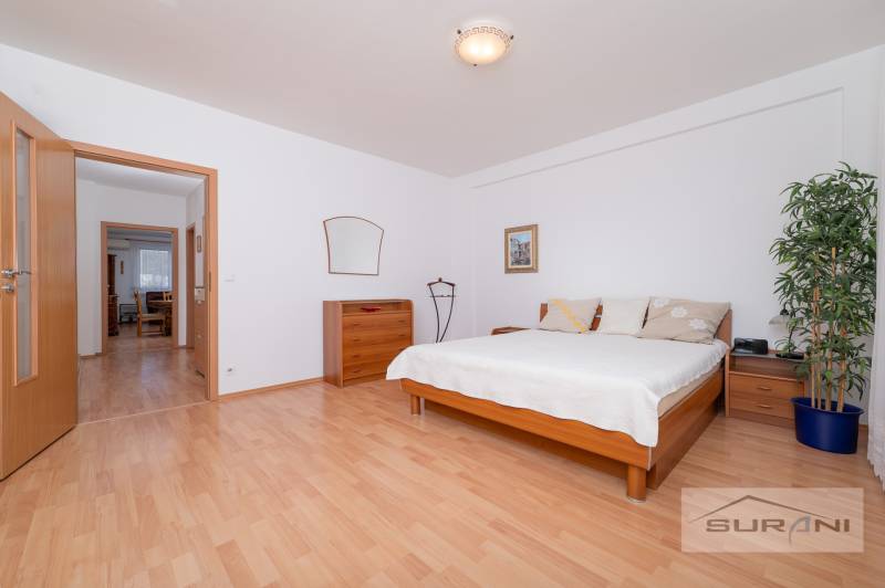 Bedroom in a 3-room apartment with a bed, dresser, and wooden decor flooring.