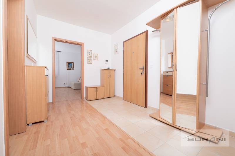 Entrance hall in a 3-room apartment with wood-patterned flooring and a mirrored wardrobe.