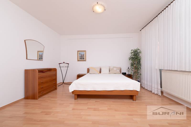 Bedroom with a bed, dresser, and wooden decor flooring in a three-room apartment.