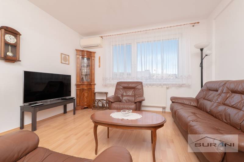 Living room in a 3-room apartment with leather furniture and wood-patterned flooring.