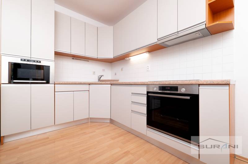 A kitchen in a 3-room apartment with white cabinets and a wood-patterned floor.
