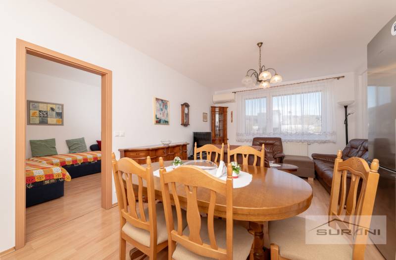 Dining table with wooden chairs in a 3-room apartment, next to the living room.