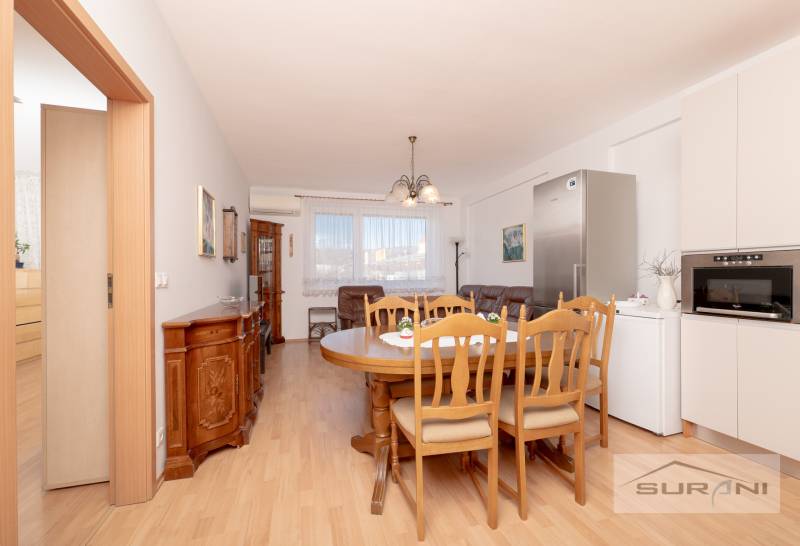 A dining room with wood-patterned flooring and furniture in a 3-room apartment.