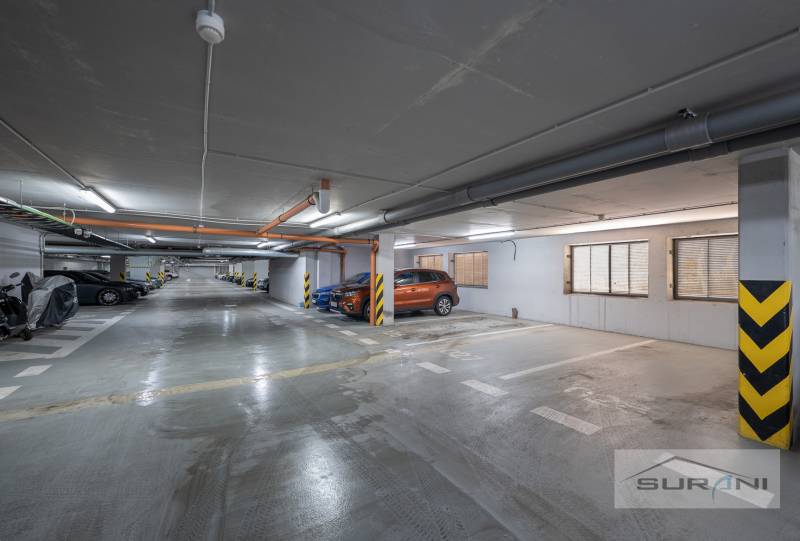 Underground parking lot with marked parking spaces and parked cars and motorcycles.