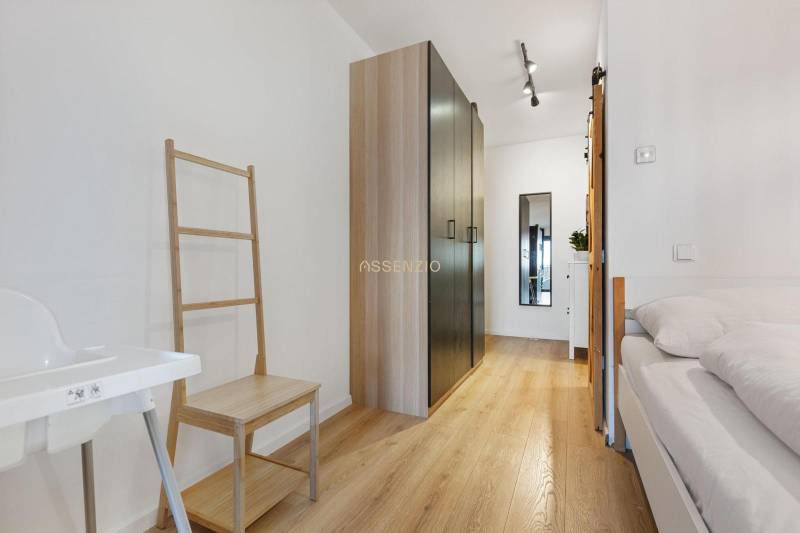 Interior of a 1-room apartment with a wooden decor floor, wardrobe, and bed.