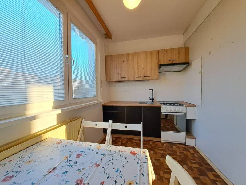 A kitchen in a 2-room apartment with a wooden decor floor and a dining table.