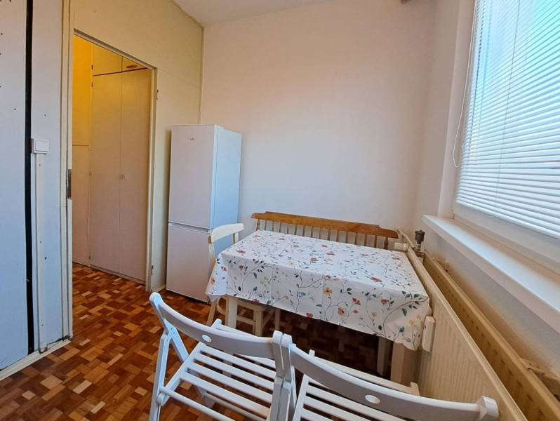 Dining room in a 2-room apartment with a wood-patterned floor and a white refrigerator.