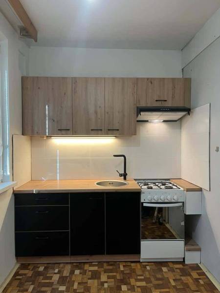 A kitchen in a 2-room apartment with a wooden cabinet and a panel floor.