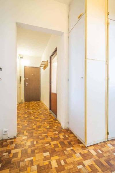 A hallway in a 2-room apartment with a wooden decor floor and a built-in wardrobe.