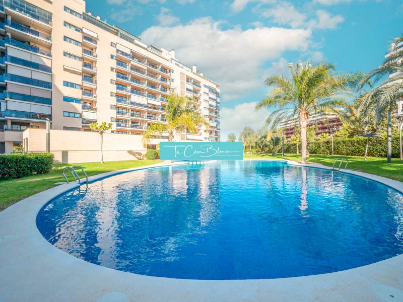 An apartment complex in Alicante with a pool and palm trees in front of a 2-bedroom apartment.