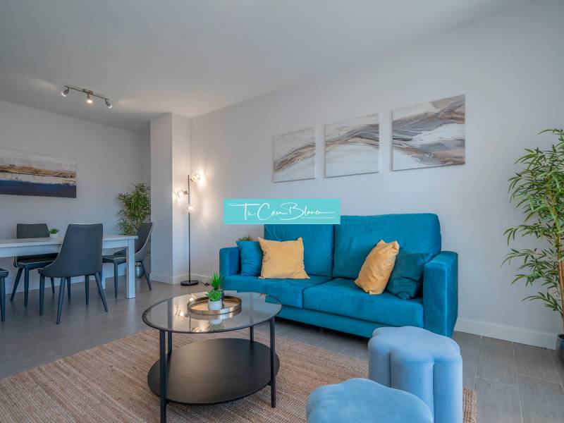 Living room in a two-room apartment with a blue sofa and a dining table.