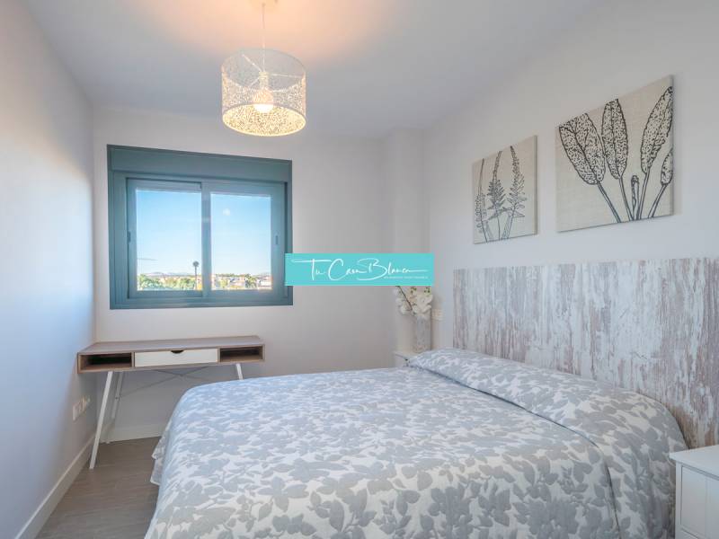 A bedroom in a 2-room apartment with a patterned blanket and decorations on the walls.