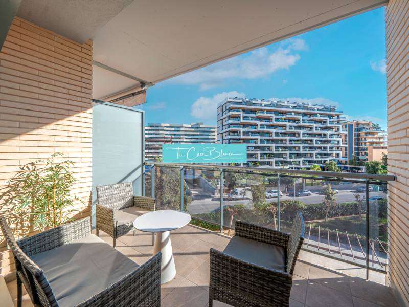 Balcony of a 2-bedroom apartment in Alicante with outdoor furniture and a view of modern buildings.