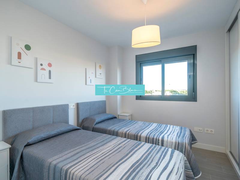 Two single beds in a 2-room apartment with a window and decorative paintings on the wall.