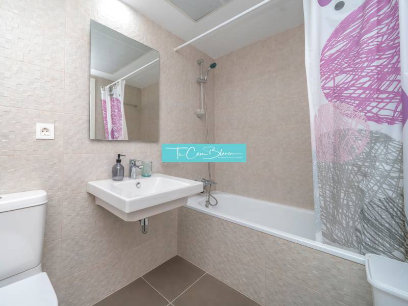 A bathroom in a 2-room apartment with modern tiles, a bathtub, and a sink.