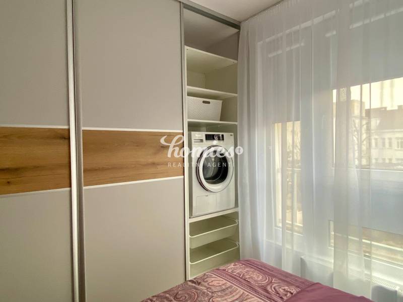 Bedroom in a 2-room apartment with a washing machine in a built-in closet and a bed.