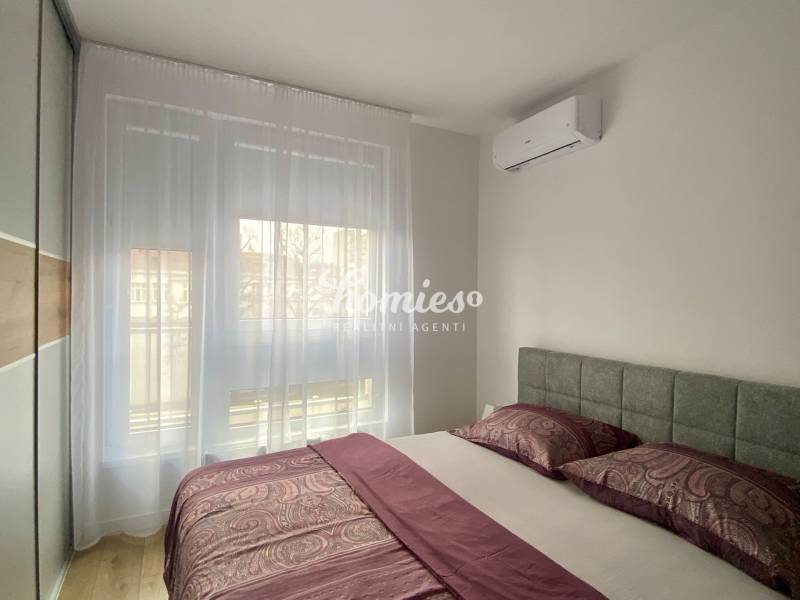Bedroom in a 2-room apartment with air conditioning and a wooden decor floor.