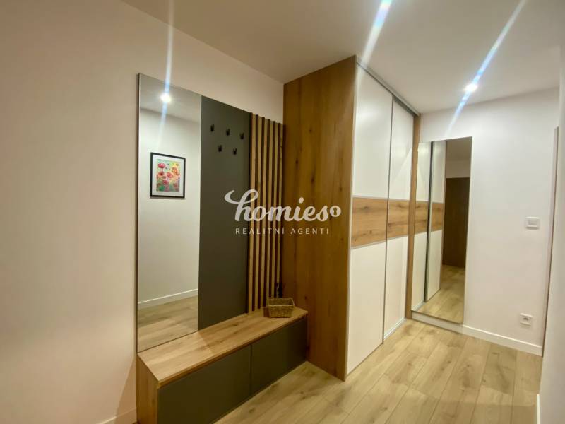 Interior of a 2-room apartment with a wooden decor floor, coat rack wall, and mirror.
