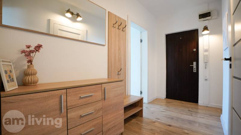 Hallway in a 3-room apartment with a wooden decor floor and wooden furniture.