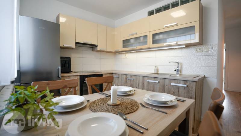 A kitchen in a 3-room apartment with a furnished dining area and a wooden decor floor.