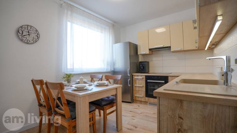 A kitchen in a 3-room apartment with a wooden decor floor, wooden table and chairs.