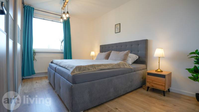 Bedroom in a 3-room apartment with a bed, nightstands, and a floor with a wood decor.