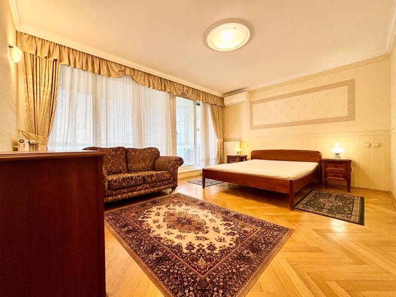 Bedroom in a 4-room apartment with a wooden decor floor and elegant furniture.