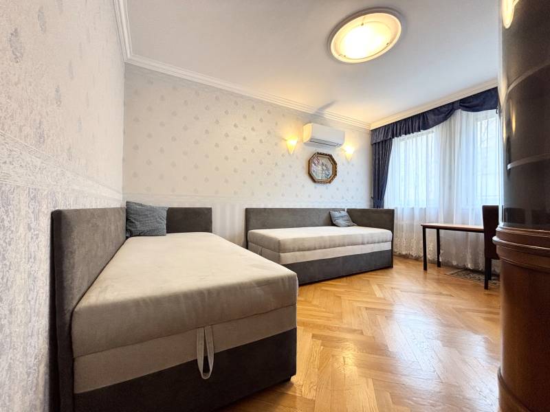 A room in a 4-room apartment with two beds, air conditioning, and a wooden decor floor.