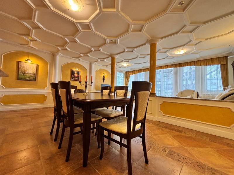 A dining room with a stucco ceiling, decorative paintings, and a wooden table, 4-room apartment.