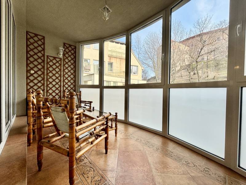 A typical winter garden for a 4-room apartment features rattan furniture and large windows.