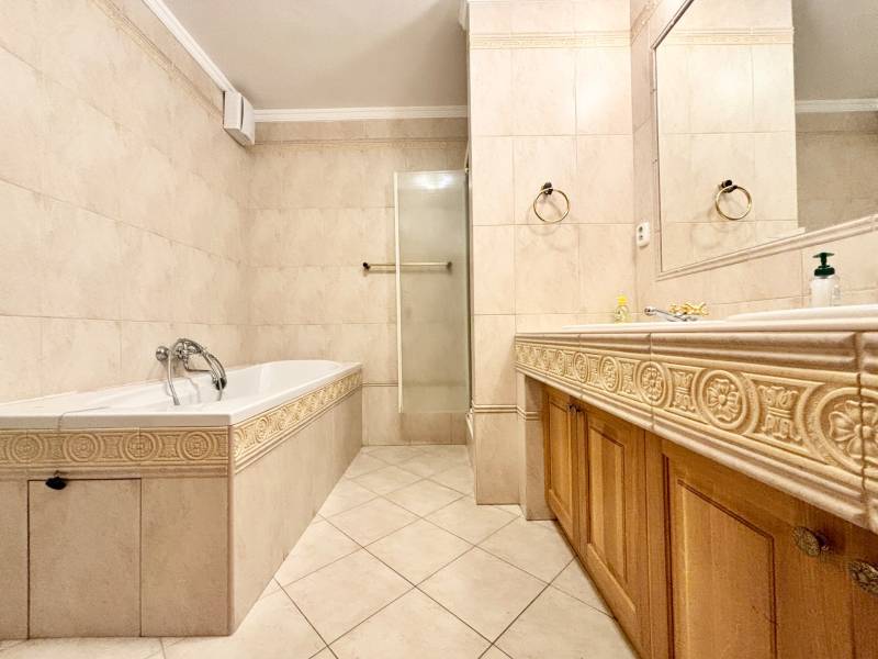 Bathroom in a 4-room apartment with a bathtub, shower corner, marble tiles, and a sink.